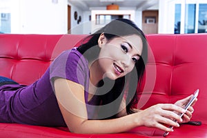 Attractive female lying on red sofa at home