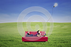 Attractive female lying on red sofa under lamp outdoor