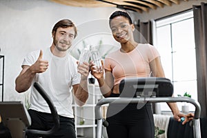 Attractive female and male working out on fitness and looking at camera.