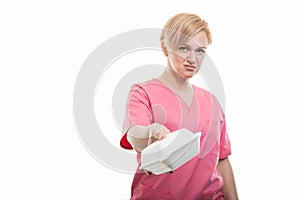 Attractive female nurse wearing pink scrubs handing lunch box
