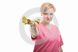 Attractive female nurse wearing pink scrubs holding measuring ta