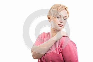 Attractive female nurse wearing pink scrubs holding shoulder like hurting