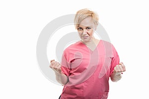 Attractive female nurse wearing pink scrubs making winner gesture