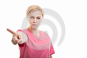 Attractive female nurse wearing pink scrubs showing denial