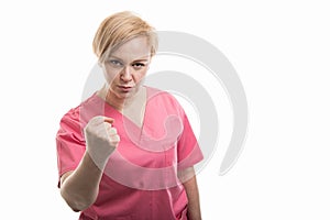 Attractive female nurse wearing pink scrubs showing fist