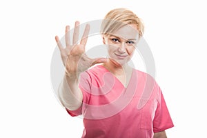 Attractive female nurse wearing pink scrubs showing number five