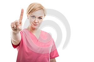Attractive female nurse wearing pink scrubs showing number one