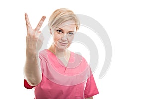 Attractive female nurse wearing pink scrubs showing number two