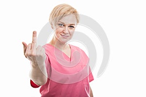 Attractive female nurse wearing pink scrubs showing obscene gesture