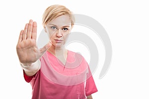 Attractive female nurse wearing pink scrubs showing stop