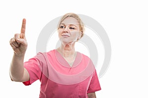 Attractive female nurse wearing pink scrubs using touchscreen