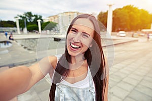 Attractive female in overalls smiling sincerely making selfie