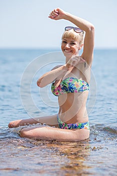 Attractive female person in bikini showing axillary hair out of seaweed at the beach photo
