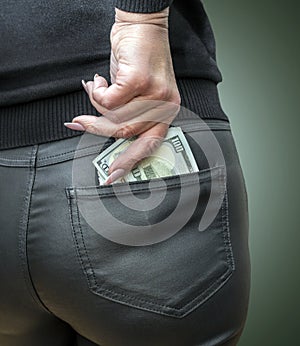 Attractive female placing wad of cash into back pocket of her jeans.
