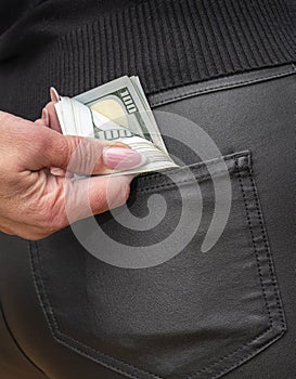 Attractive female placing wad of cash into back pocket of her jeans. Out of pocket expenses