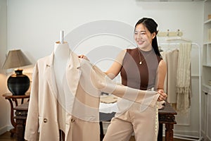 An attractive female tailor is working in her studio, checking her suit pattern on a tailor dummy