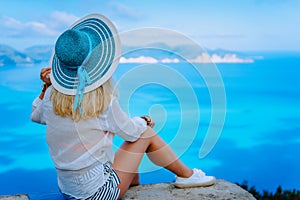 Attractive female tourist with turquoise sun hat enjoying amazing azure seascape, Greece. Cloudscape shadows on the sea