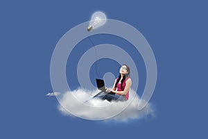 Attractive female using laptop on cloud under lamp