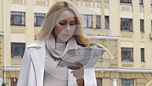 Attractive female using paper map to navigate in unknown area, destination