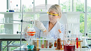 Attractive female young scientist smiling and looking in table equipment the forensic laboratory with foreground of tube and