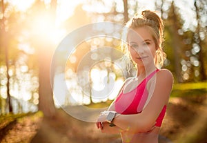 Attractive fit athletic woman in a forest, wearing smart watch, taking a break from intense workout. Sport, fitness, workout