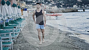 Attractive athletic young man walking on beach