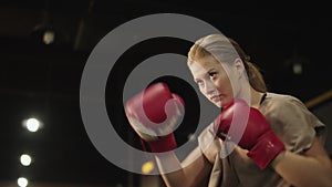Attractive fit girl boxing in fitness center. Sport woman doing punches at gym