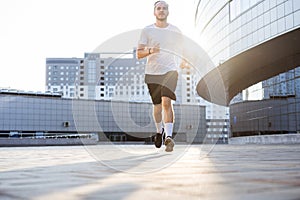 Attractive fit man running in the city at sunset. Fitness, workout, sport, lifestyle concept