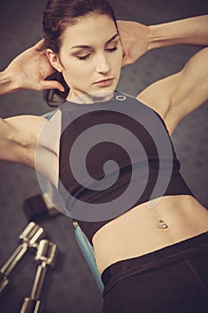 Attractive fit woamn working out abs in fitness gym, making ab i