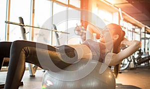 Attractive fit woman doing sit-ups on a fitness ball in gym.