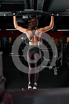 Attractive fit woman works out with dumbbells as a fitness conceptual over dark background.
