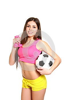 Attractive fitness girl with dumbbells and a soccer ball on a white background