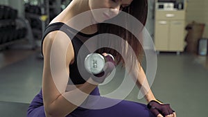 Attractive fitness girl practicing exercises with dumbbells in the gym. Young woman lifting weight in sport club