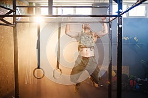 Attractive fitness guy doing pull-ups on the crossbar during training in the modern gym. Close up shot.
