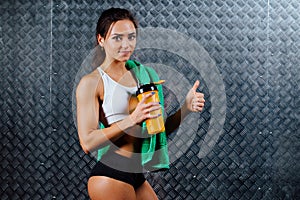 Attractive fitness woman with bottle and towel indoor portrait.