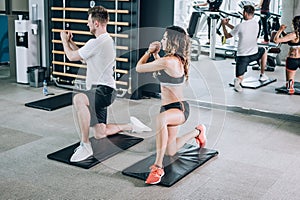 Attractive fitness woman with coach doing hard exercise in gym