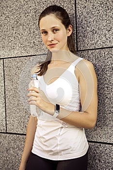 Attractive fitness woman drinking water after running.