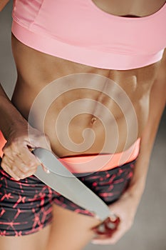Attractive fitness young woman showiong her perfect abs. Health concept. Fit woman holding rubber band.