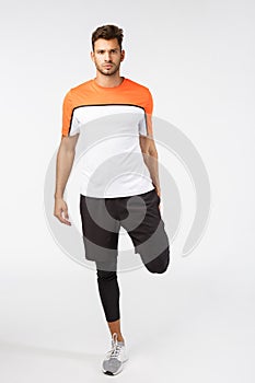 Attractive football player warm-up muscles before match. Serious-looking determined sportsman in activewear, stretch