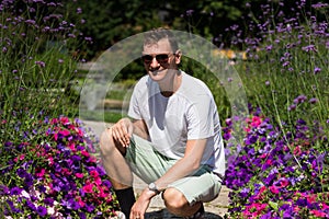 Attractive fourty year old man with sunglasses and white T-shirt posing in the botanical garden