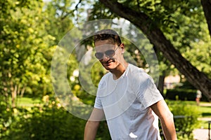 Attractive fourty year old man with sunglasses and white T-shirt posing in the botanical garden