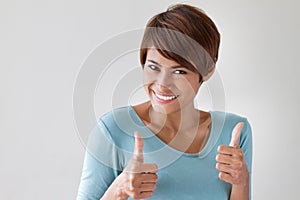 Attractive, friendly, smiling woman giving two thumbs up