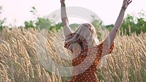 Attractive fun hippie blonde woman in the field at sunset having good time outdoors. Slow motion. Female spinning in the field