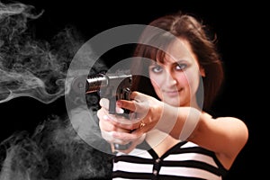 Attractive girl aiming with gun with smoke