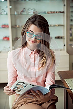 Attractive girl on appointment in eye specialist office. Portrait of european young brunette customer sitting in glasses