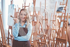 Attractive girl in an apron on the background of easels