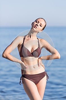 Attractive girl in bikini posing arms akimbo at the sea