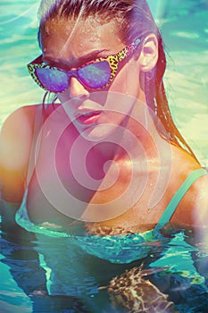 Attractive girl in bikini and sunglasses in pool