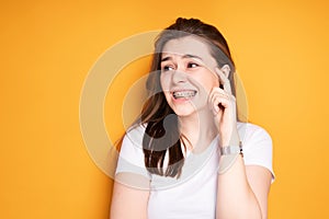 Attractive girl with braces grimaces from pain in her teeth, looking away. Healthy smile concept