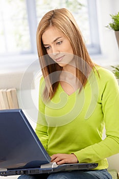 Attractive girl browsing internet at home in green